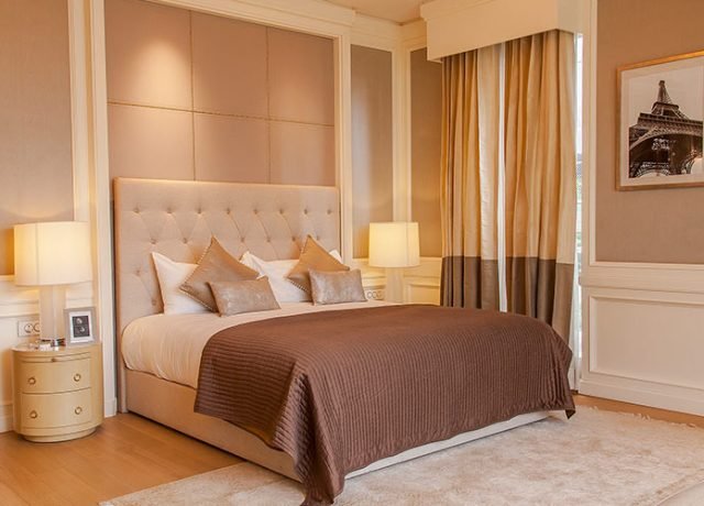 Luxury bedroom with a plush bed, elegant decor, soft lighting, and large windows showcasing a sophisticated design, reflecting Rizo Homes' commitment to high-end residential living.