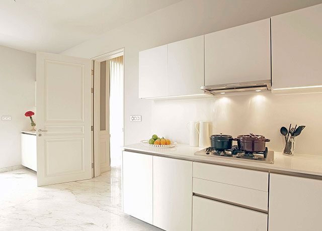 Modern kitchen with quartz countertops, sleek white cabinetry, and BOSCH appliances, featuring a gas stove, pots, and a fruit bowl, illuminated by soft lighting, showcasing luxury living in residential design.